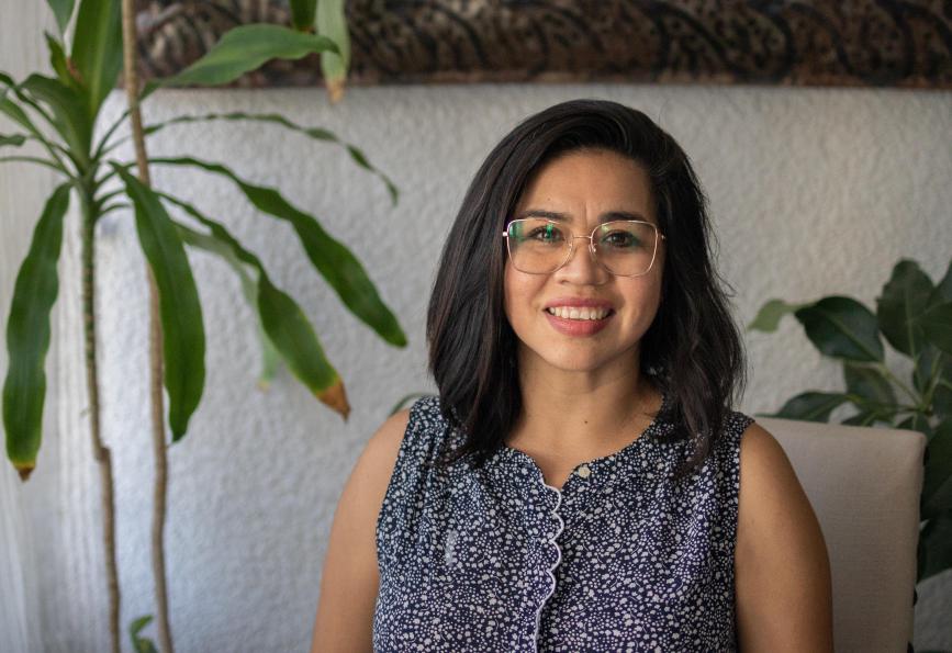Cecilia Paola Espinoza, a World Mosquito Program volunteer, sitting in front of a grey wall